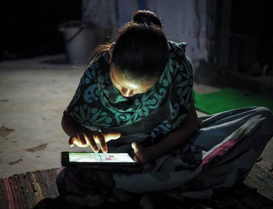 Image of young girl looking at a tablet computer at night using her hands.